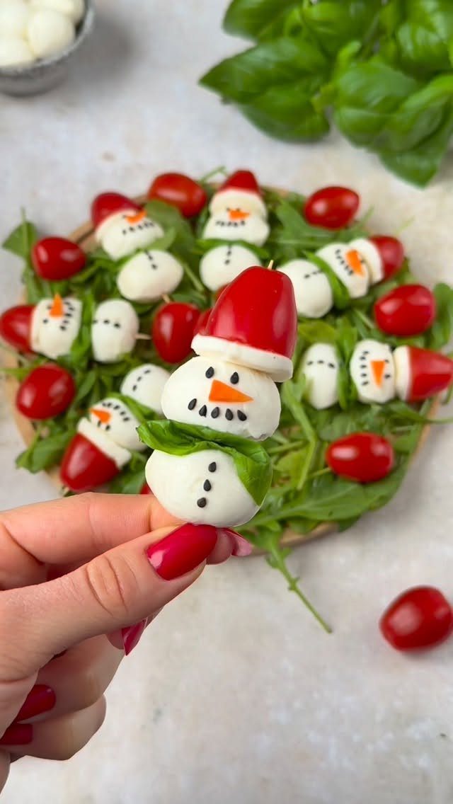 Caprese skewers assembled as snowmen with mozzarella and cherry tomatoes on arugula