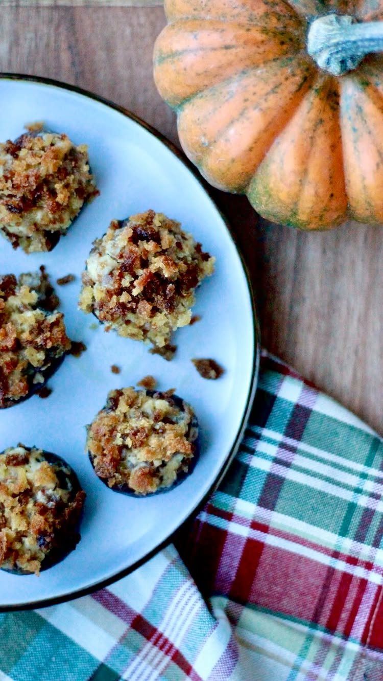 Stuffed mushroom caps with golden filling on a blue plate beside a pumpkin.