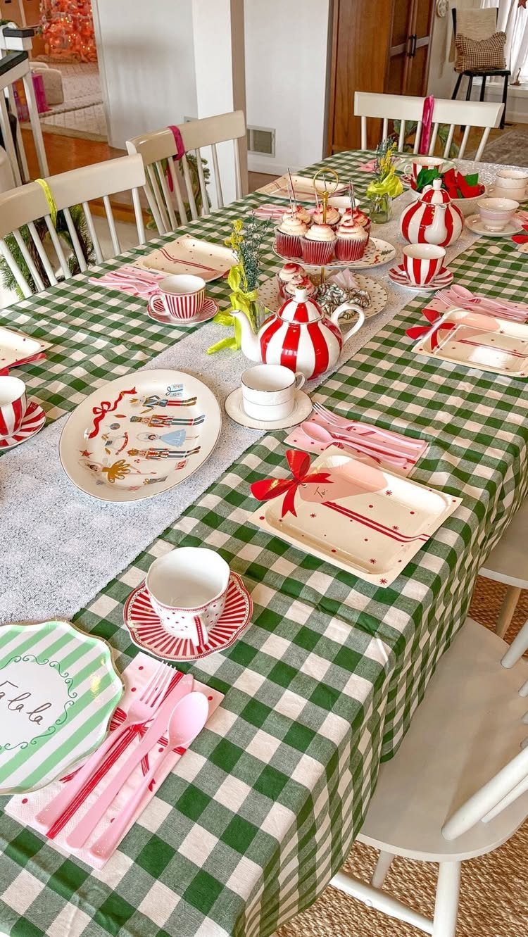 Festive table setting with green checkered cloth, red striped teaware, and cupcakes.