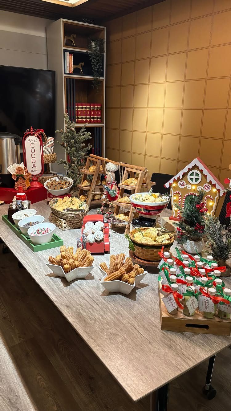 Christmas party food spread on a wooden table with a gingerbread house decoration.