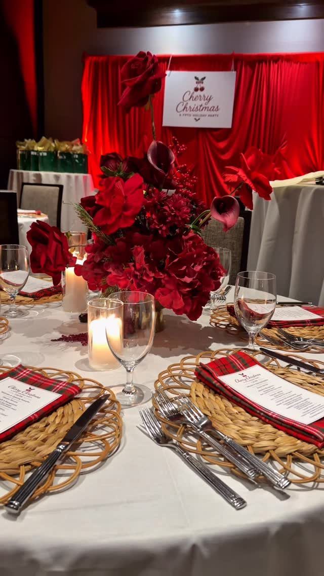 Dinner table set with red floral centerpiece, plaid napkins, and Cherry Christmas sign.