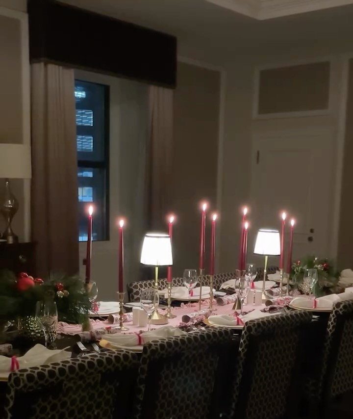 Formal dining table set with red candles and greenery for a Christmas dinner.