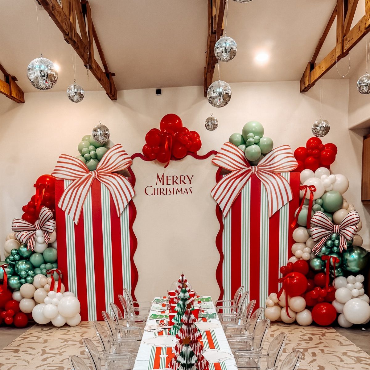 Christmas party decorations with giant striped gift boxes, balloon arches, and disco balls.