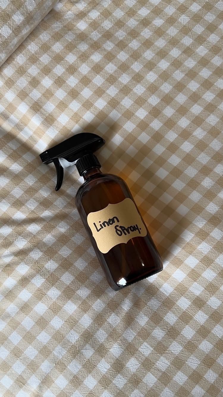 Amber glass spray bottle with linen spray label on gingham fabric background