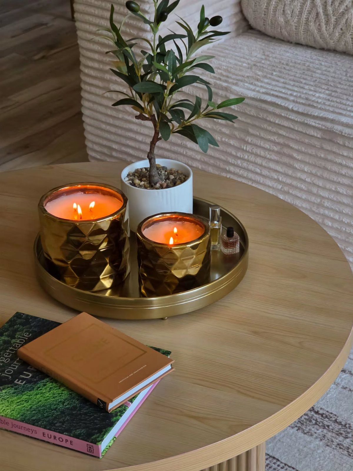 Gold faceted glass candle holders and a small olive tree on a tray.