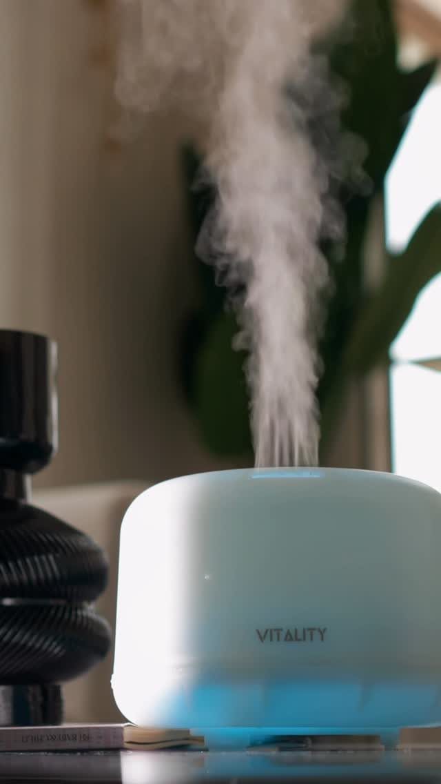 White essential oil diffuser emitting a plume of mist in a home setting.