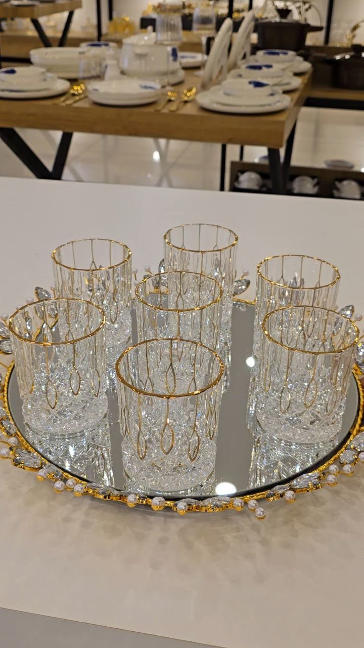 Gold-rimmed glass tumblers on a mirrored tray with a decorative gold beaded edge.