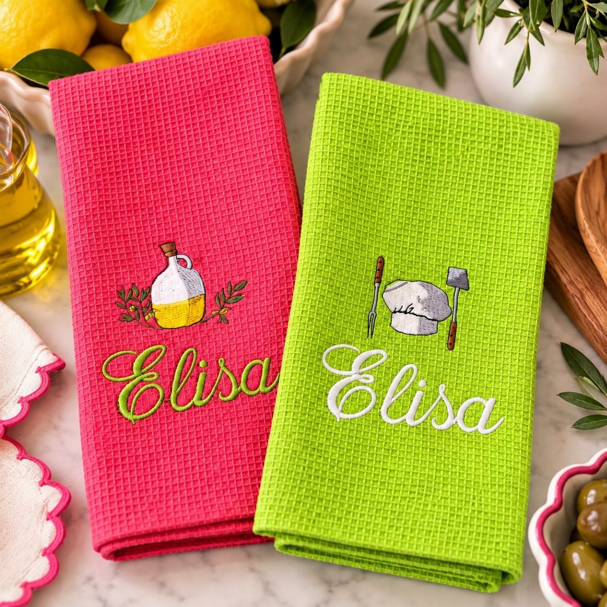 Pink and lime green embroidered kitchen towels with the name Elisa on marble.