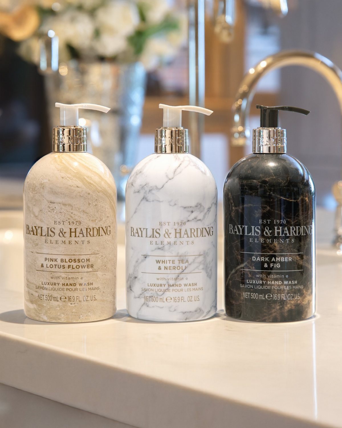 Three marble-patterned luxury hand soap bottles on a white marble bathroom counter.