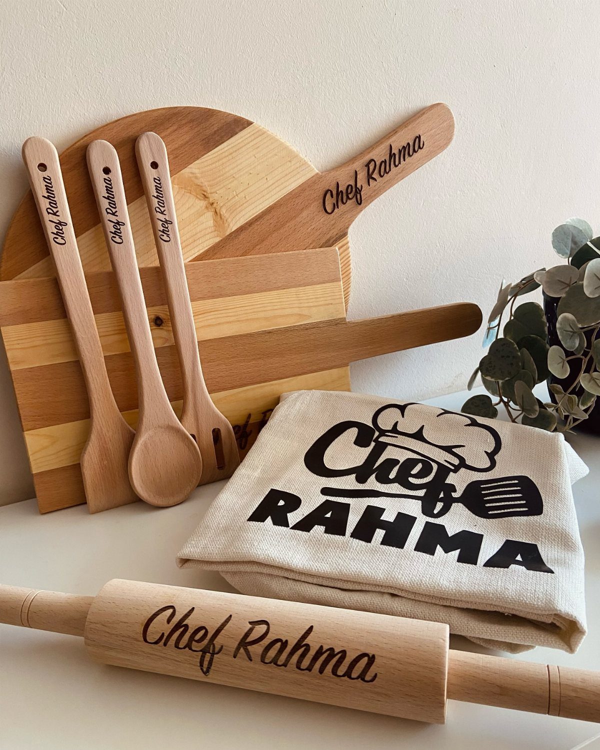 Personalized wooden kitchen utensils, cutting board, and apron engraved with Chef Rahma.