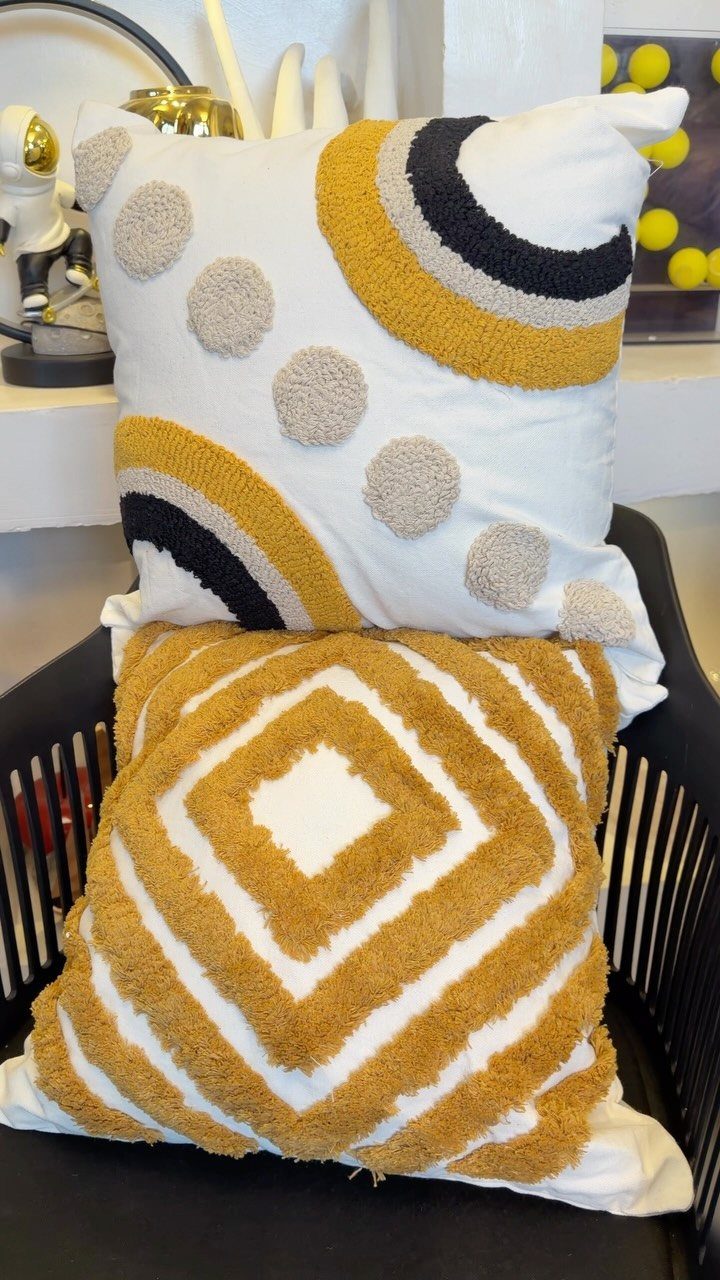 Two textured decorative throw pillows with yellow and white geometric patterns on a chair