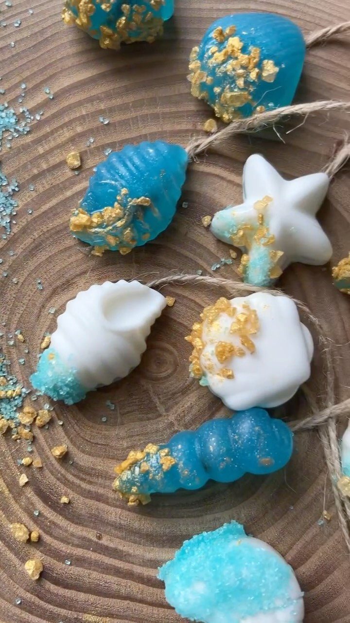 Blue and white cake pops with gold flakes on a wooden slice.