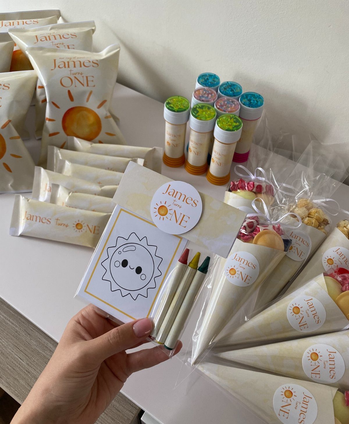 Coloring kits and themed snack bags arranged as party favors for a first birthday.