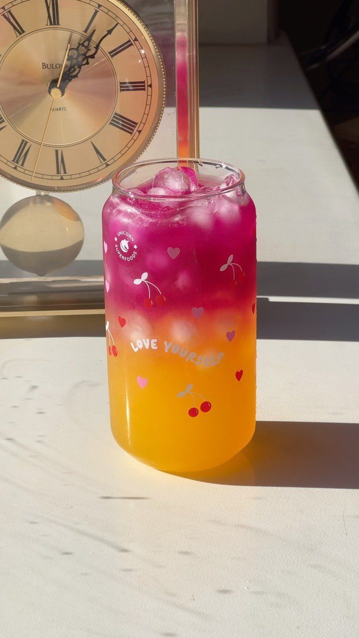 Layered pink and yellow drink in a decorated glass with a gold clock background