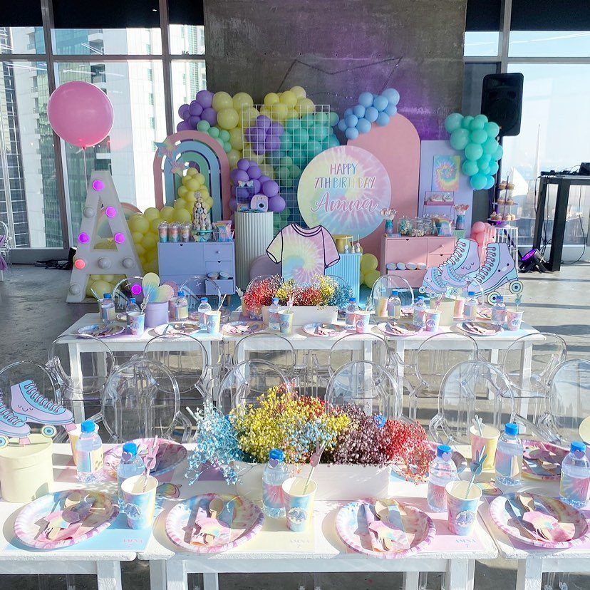 Pastel balloon arch and colorful table settings for a birthday party celebration.