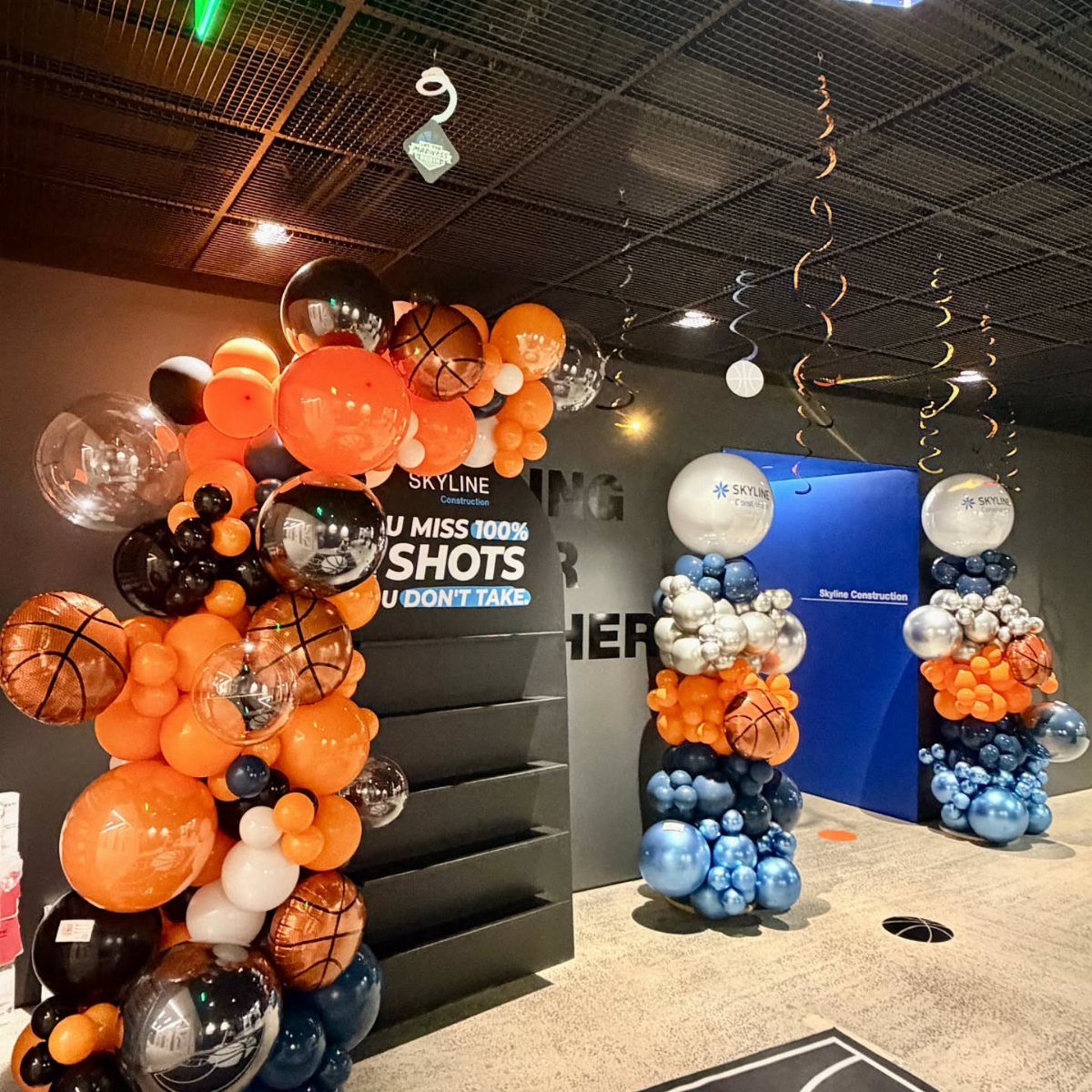 Basketball themed balloon arches in orange, blue, and black for a corporate event.