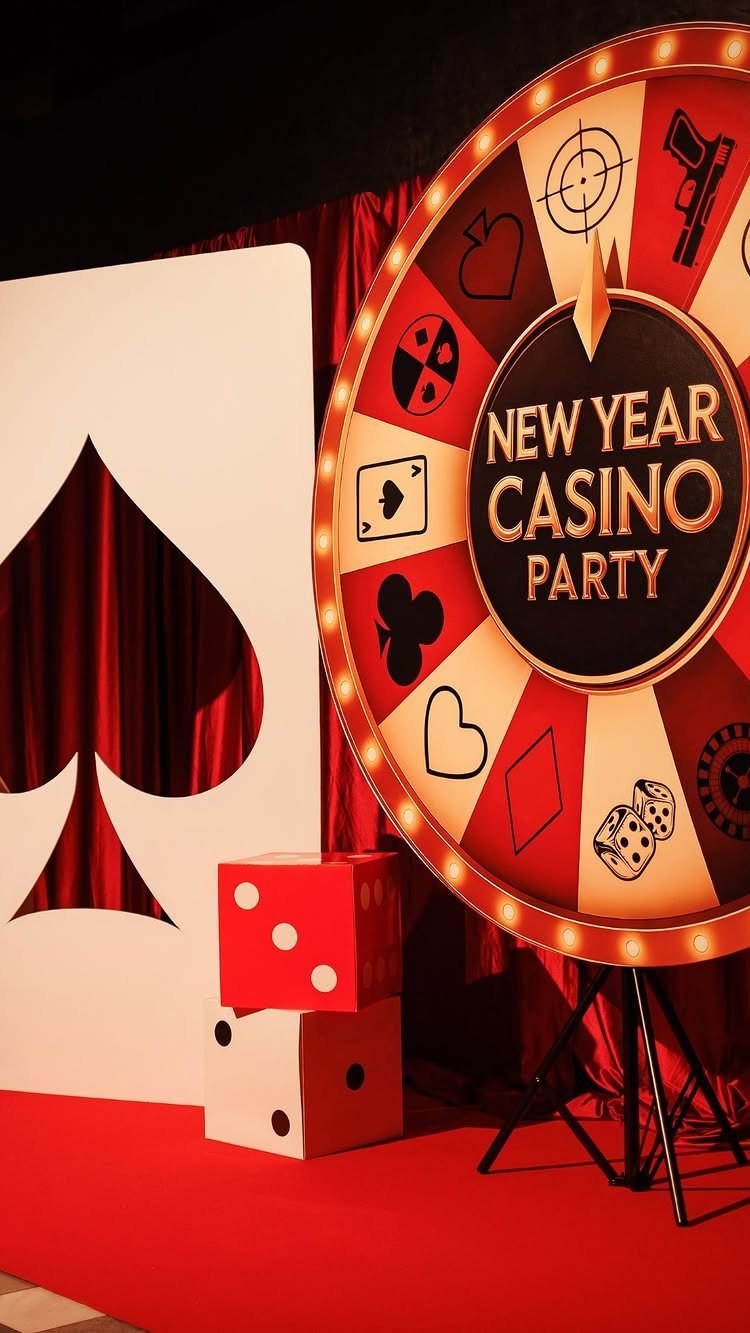 Casino party decorations featuring a large circular sign, oversized dice, and a spade cutout.