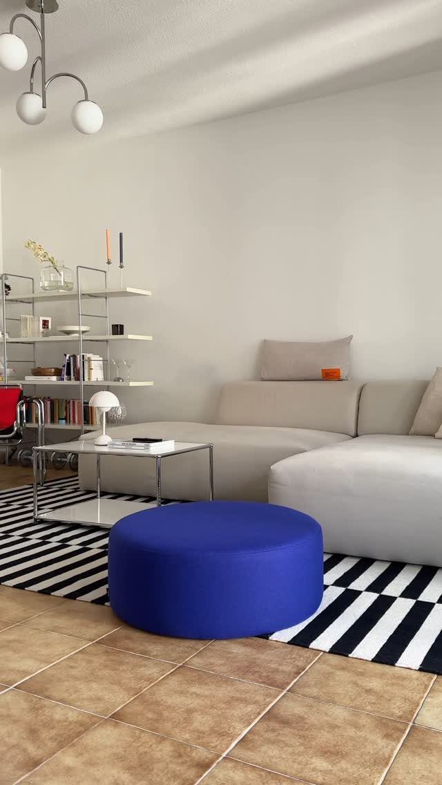 Bright blue circular pouf on a striped rug in a modern living room.