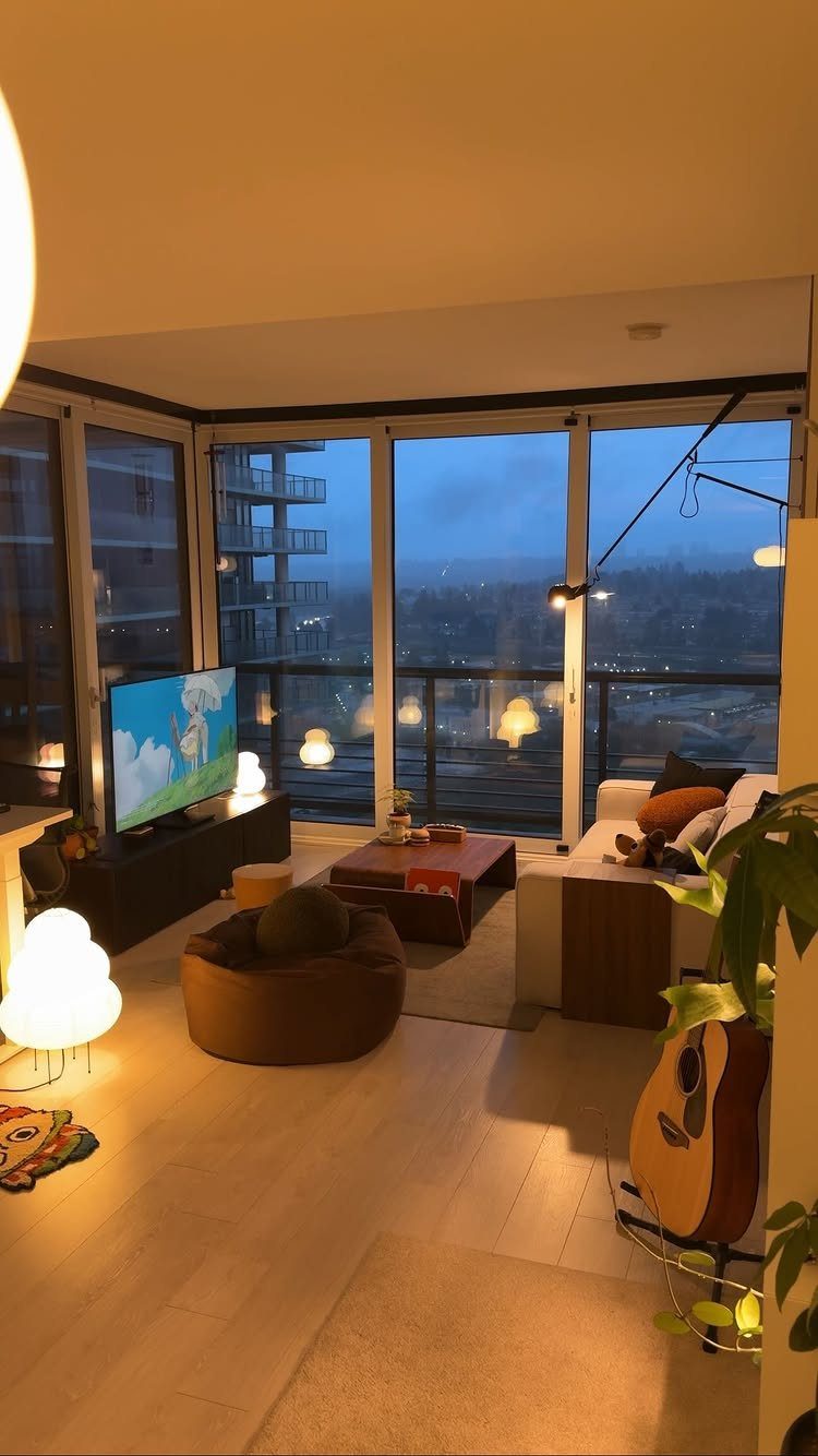 Cozy living room with warm glowing lamps, a white sofa, and city views.