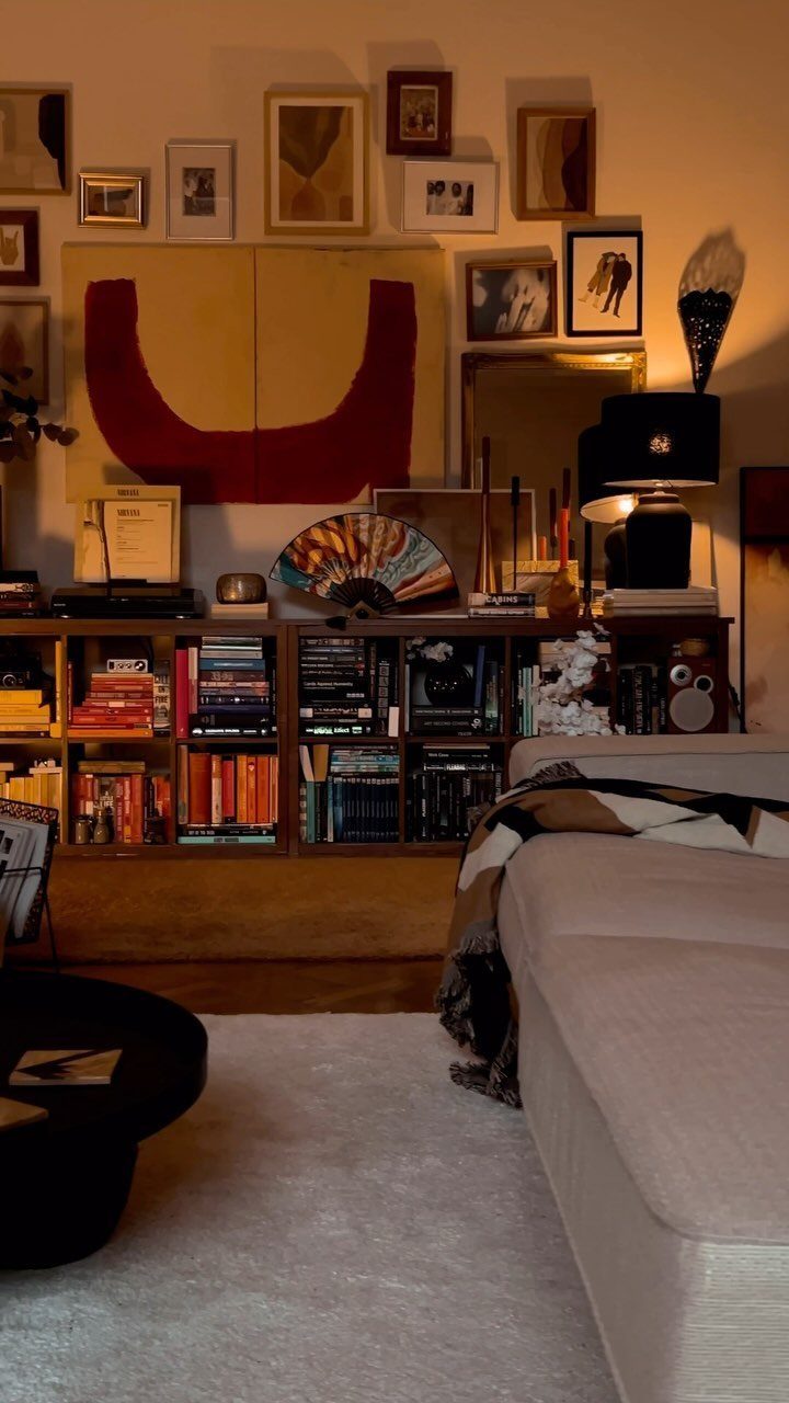 Beige sofa and wooden bookshelf in a room with a gallery wall.