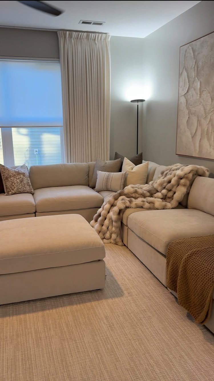 Beige sectional sofa with fluffy white throw and ottoman in a cozy living room