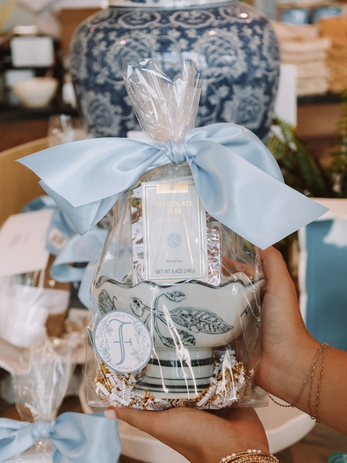 Gift wrapped ceramic bowl and chocolates tied with a light blue satin bow.