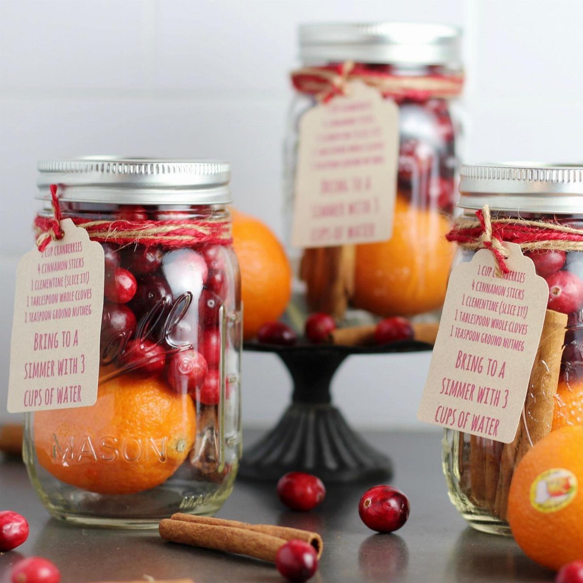 Mason jars filled with oranges, cranberries, and cinnamon sticks as homemade gift sets.