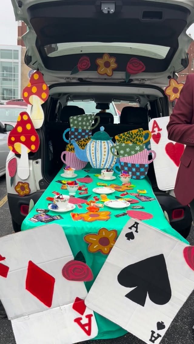 Whimsical Alice in Wonderland tea party setup in a car trunk with oversized teapots.