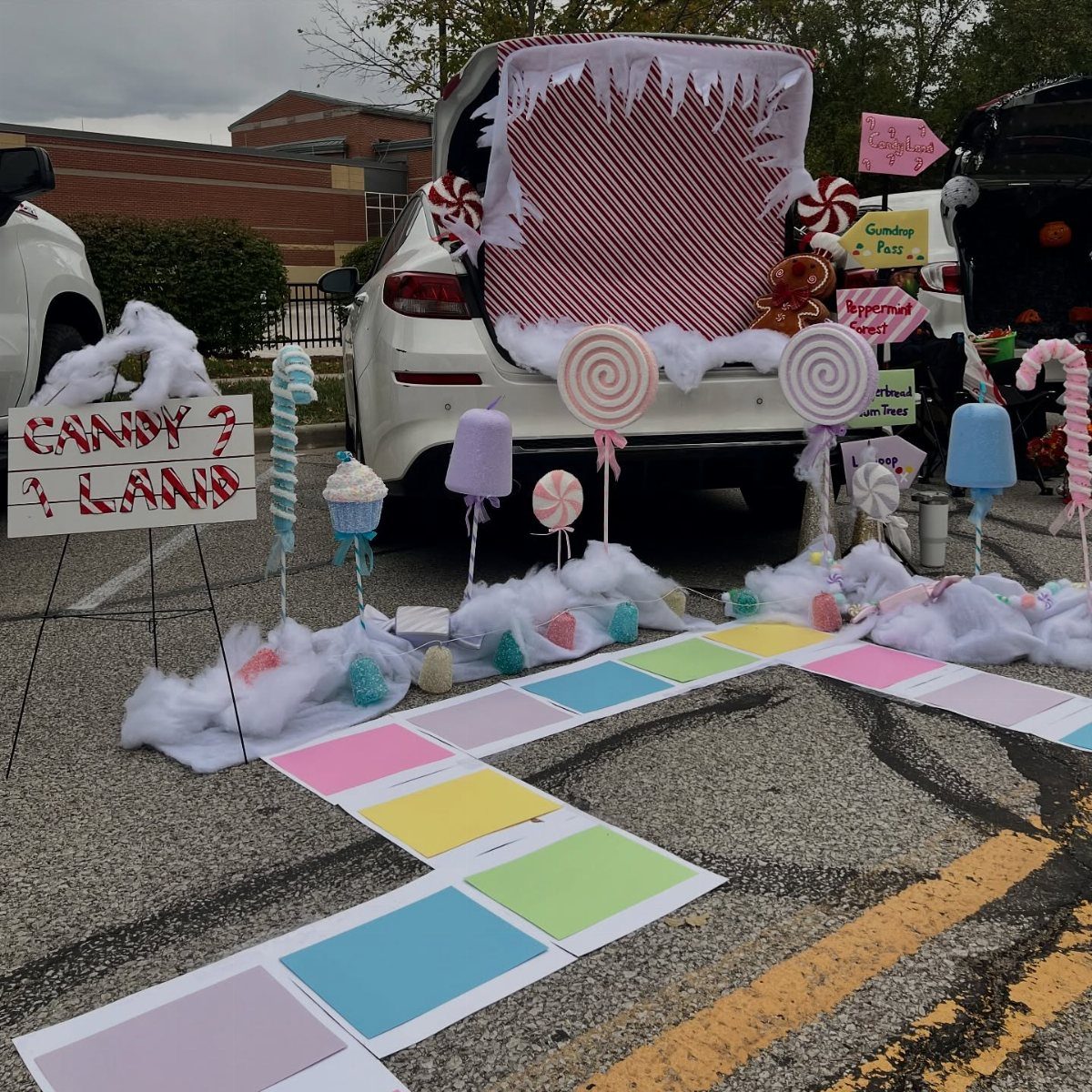 Candy Land themed car trunk with colorful lollipops and a rainbow paper path.