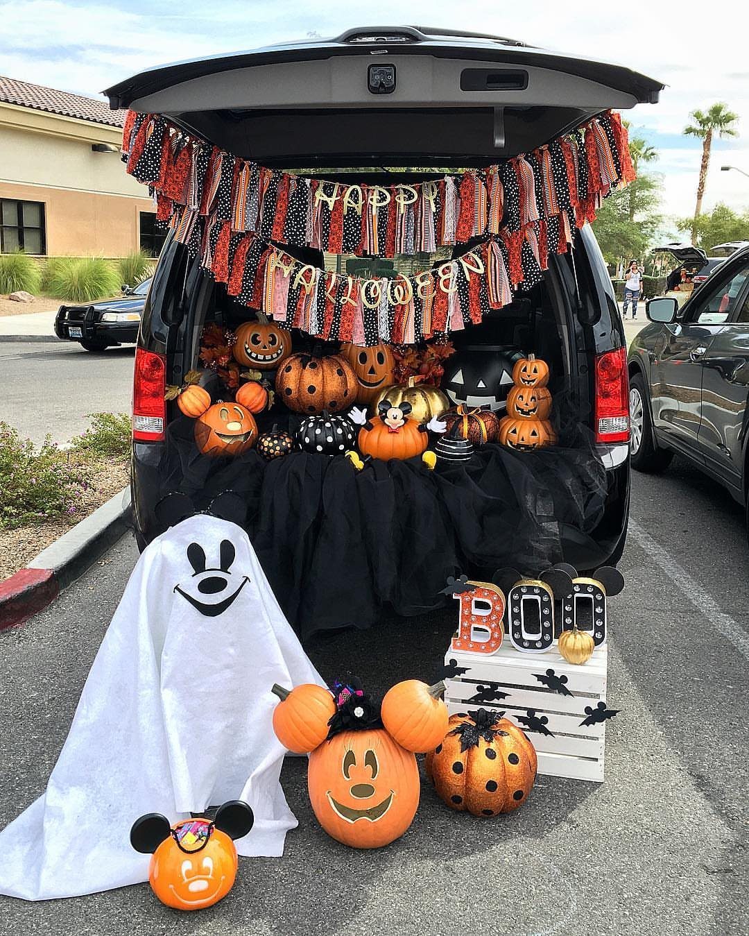 Black SUV trunk decorated with Mickey Mouse themed pumpkins and a white ghost.