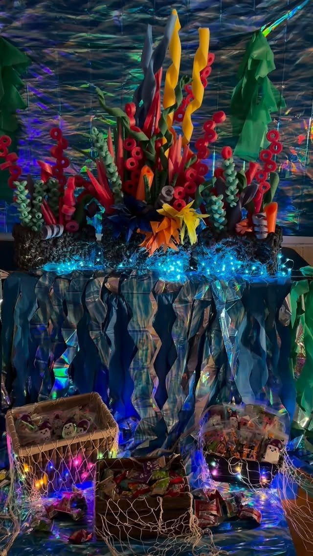 Underwater ocean scene with colorful coral, blue lights, and candy in nets.