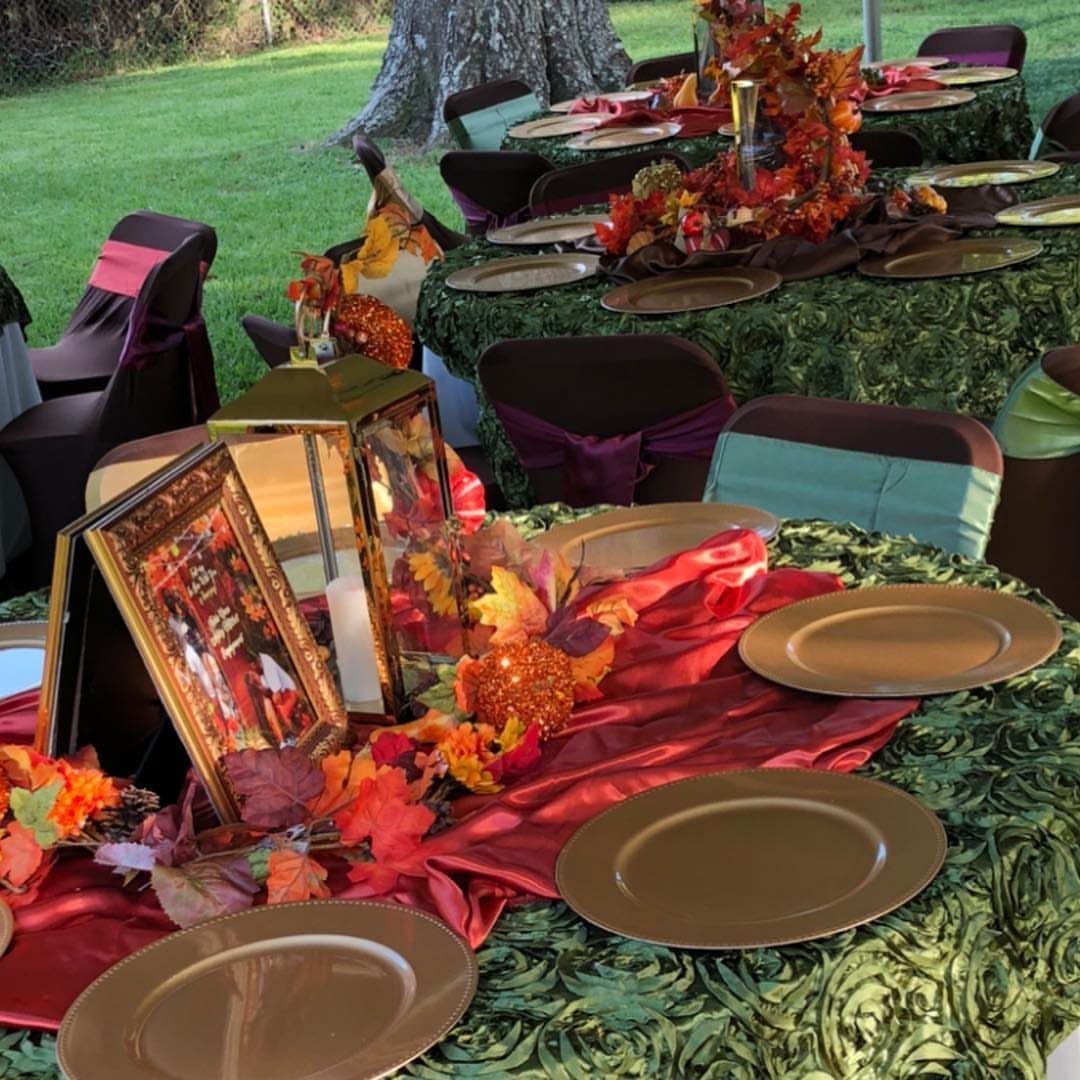 Autumn party tables with gold plates, red runners, and fall leaf centerpieces outdoors.