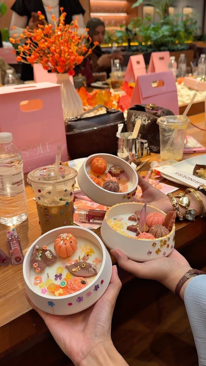 Decorative candles with pumpkin wax melts held in white bowls at a party.