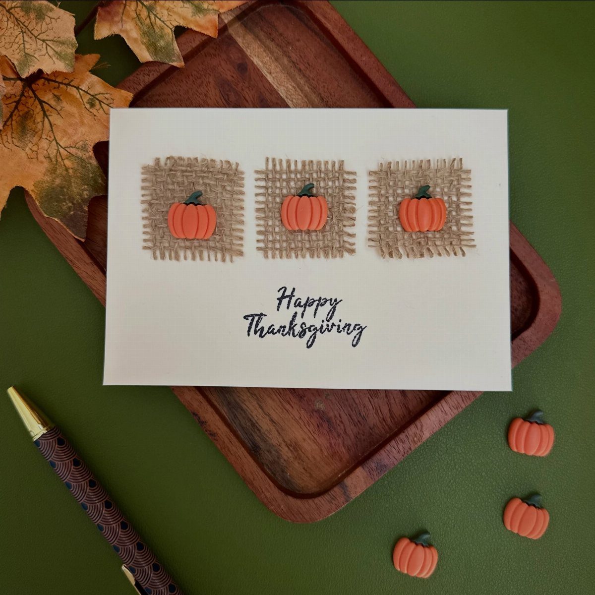 Thanksgiving greeting card with miniature pumpkins on a wooden tray with autumn leaves.