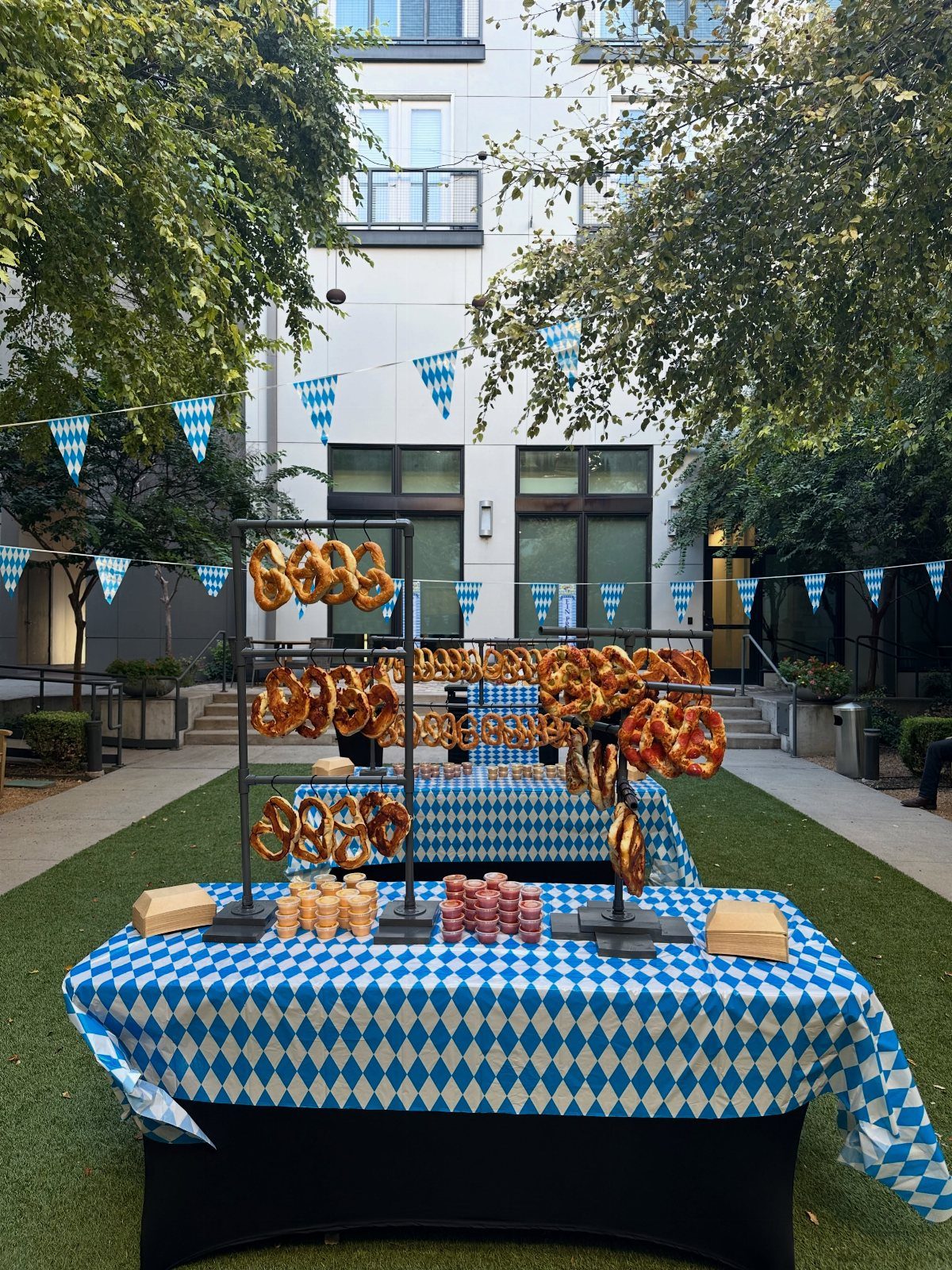 Pretzels on stands atop blue and white checkered tables with festive bunting flags.