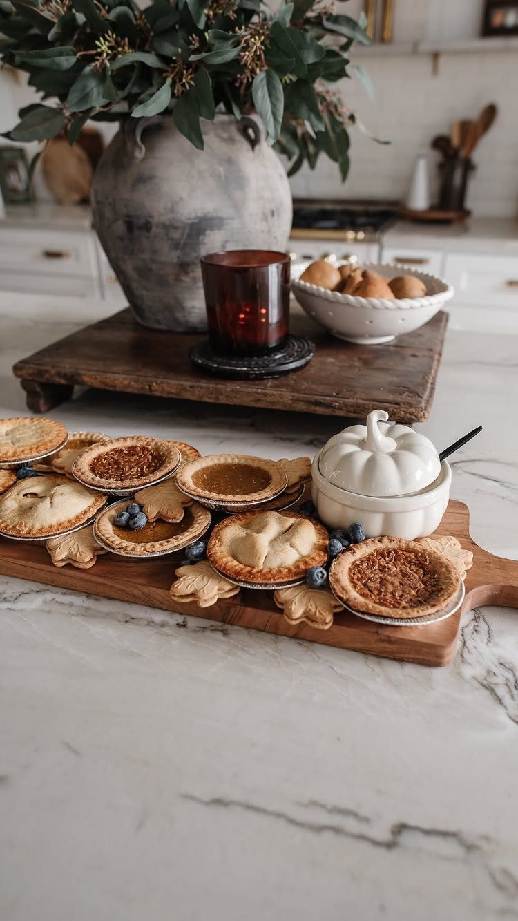 Miniature pies and leaf cookies arranged on a wooden board with autumn decor.