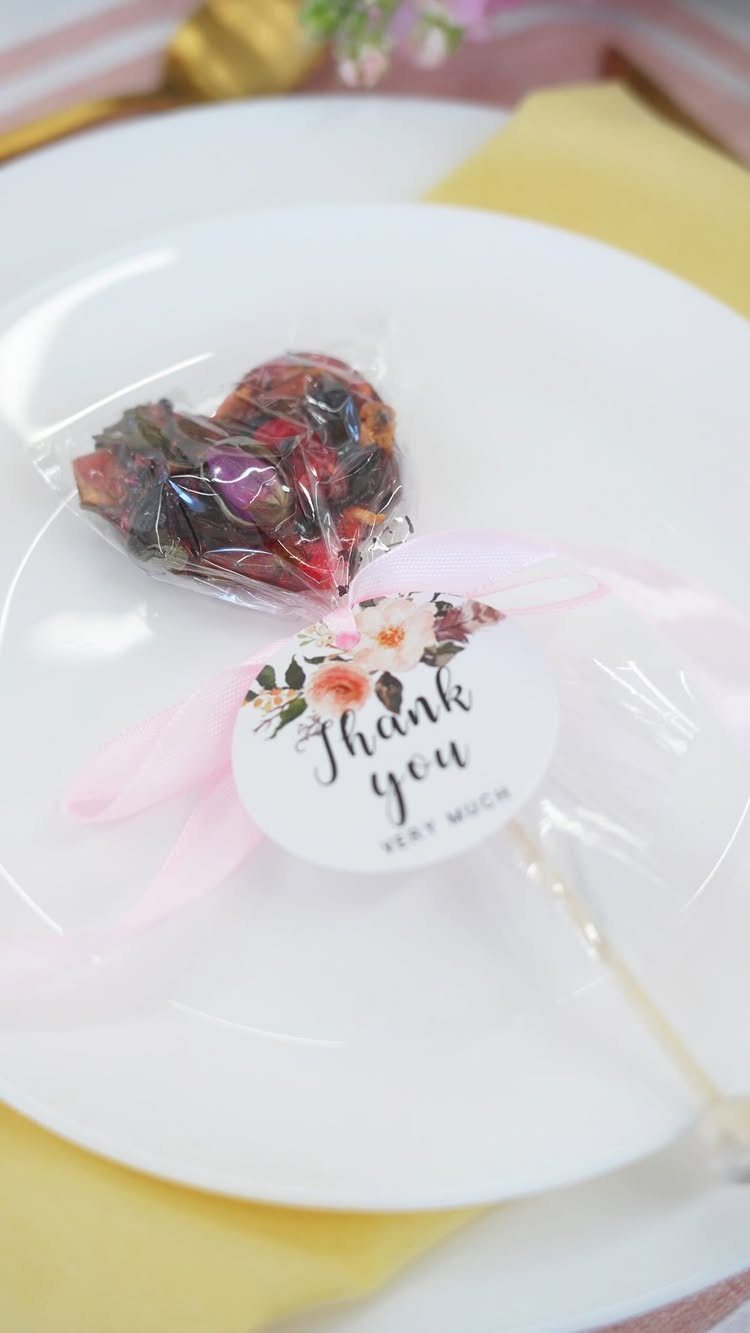 Heart-shaped floral lollipop with a thank you tag on a white plate