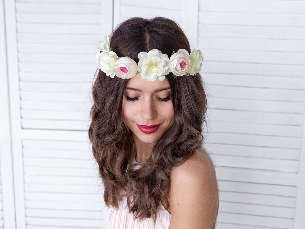 Woman with wavy brown hair wearing a white floral flower crown.