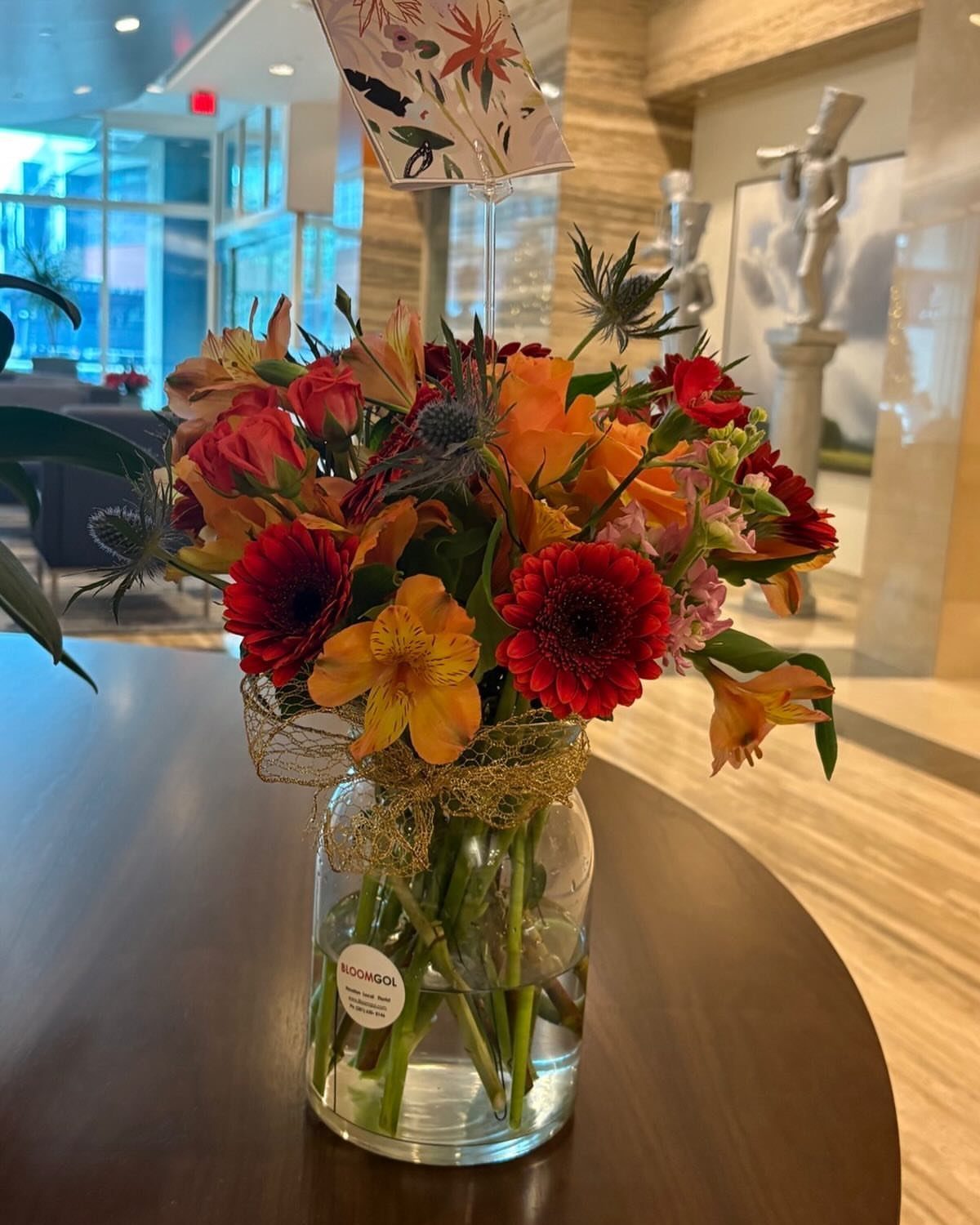 Colorful bouquet of red and orange flowers in a glass vase on wooden table