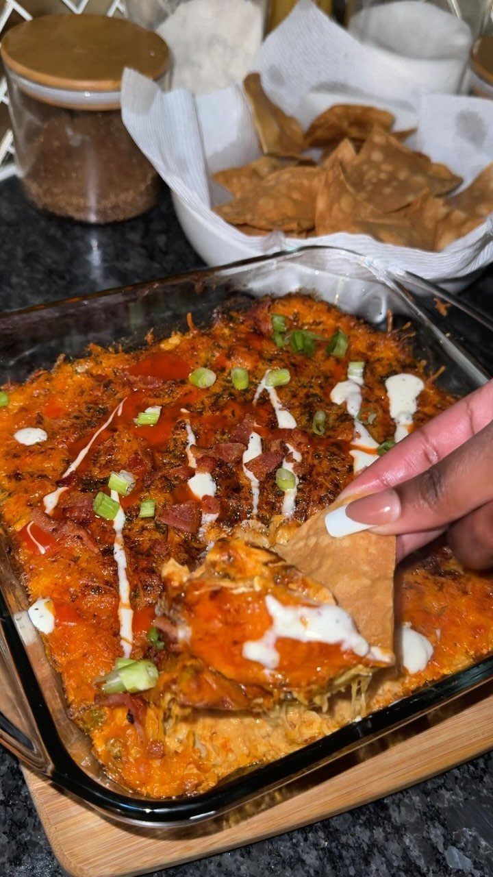 Buffalo chicken dip in a glass dish with a chip scooping some out.