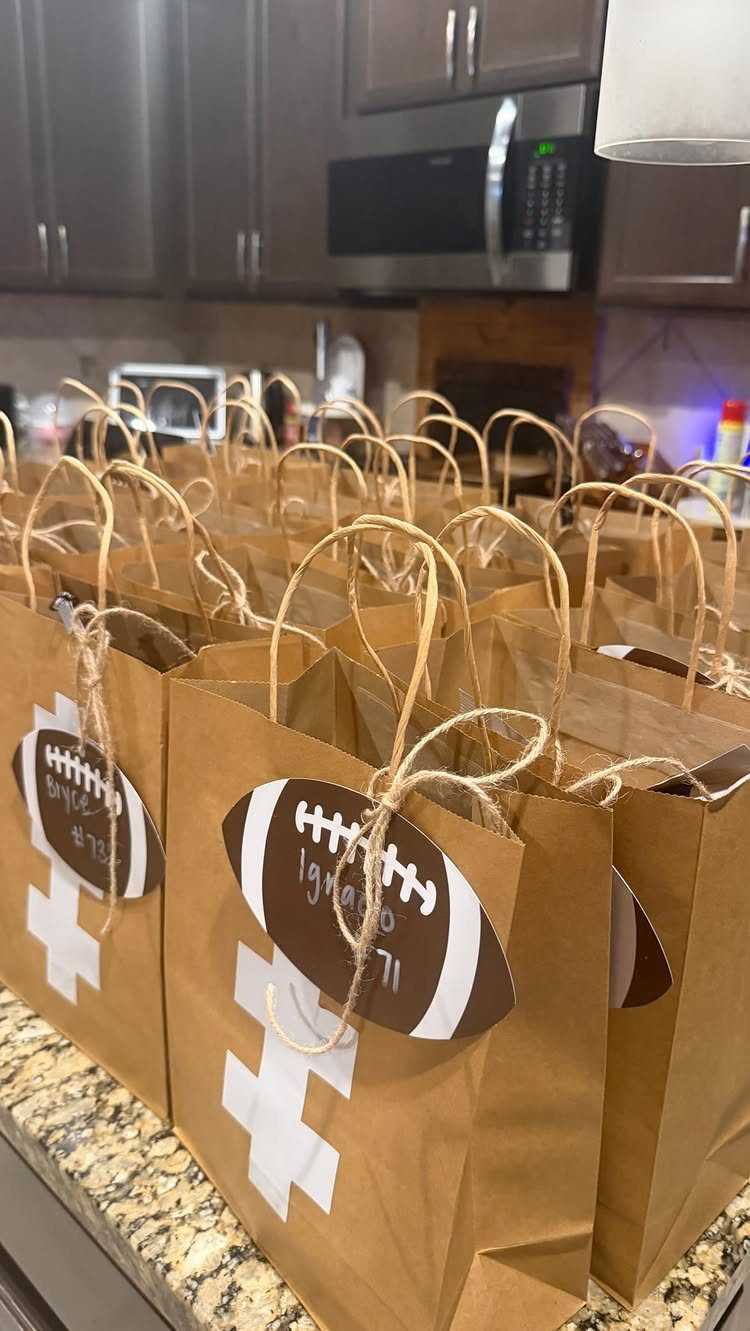 Brown paper gift bags with football tags and goalpost designs on a kitchen counter.