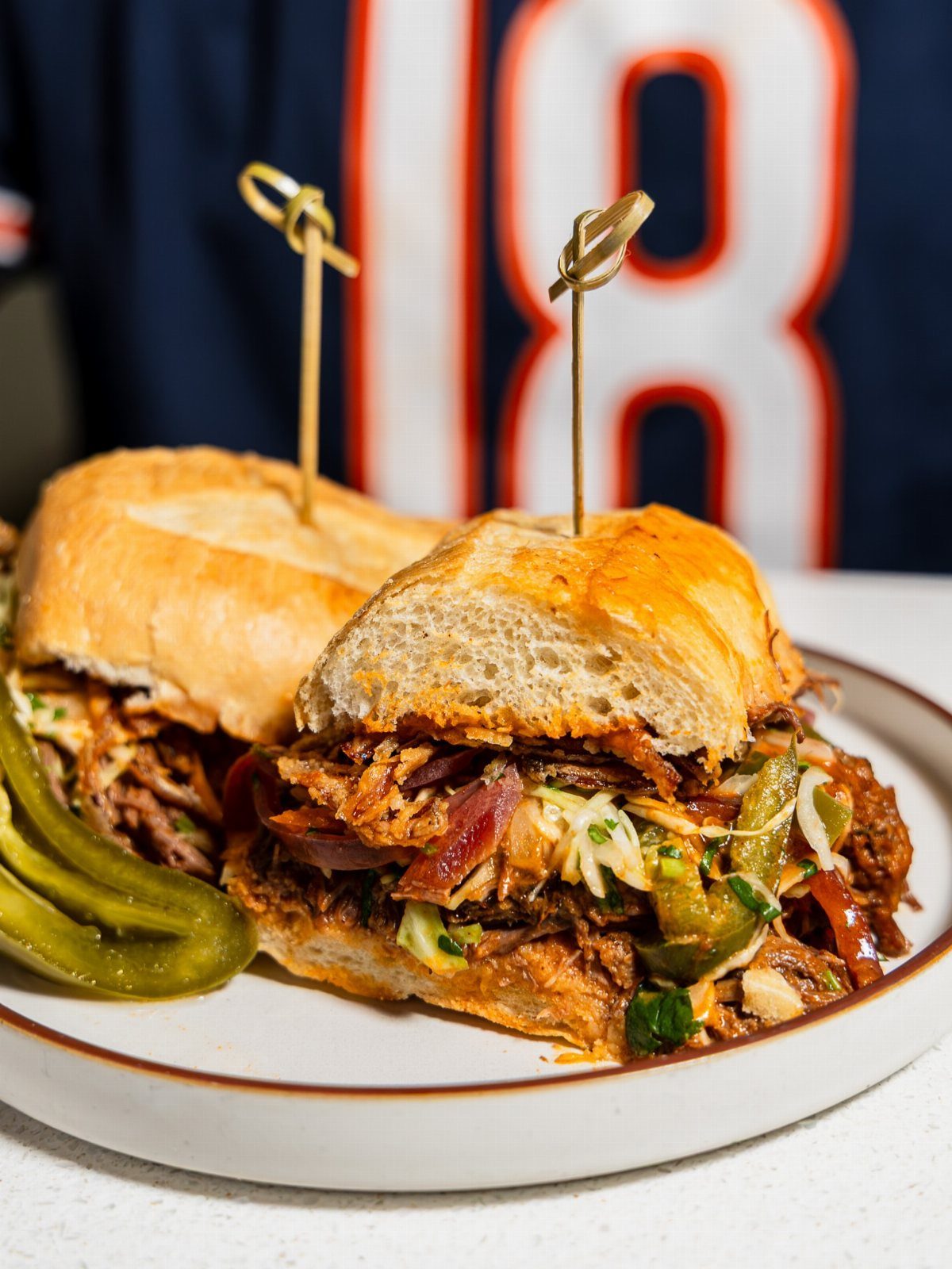 Pulled pork sandwiches with coleslaw and pickles on a plate before a jersey.