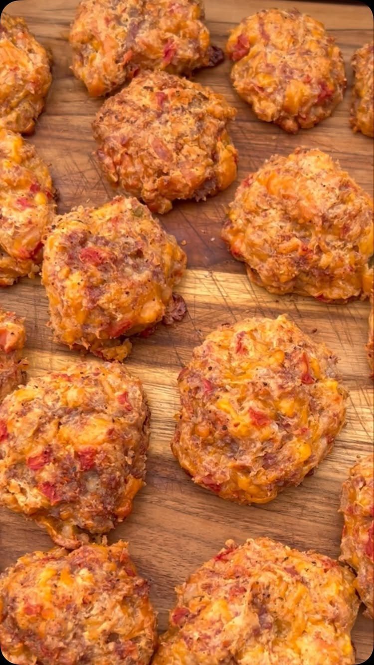 Golden-brown cream cheese sausage balls arranged on a wooden cutting board.