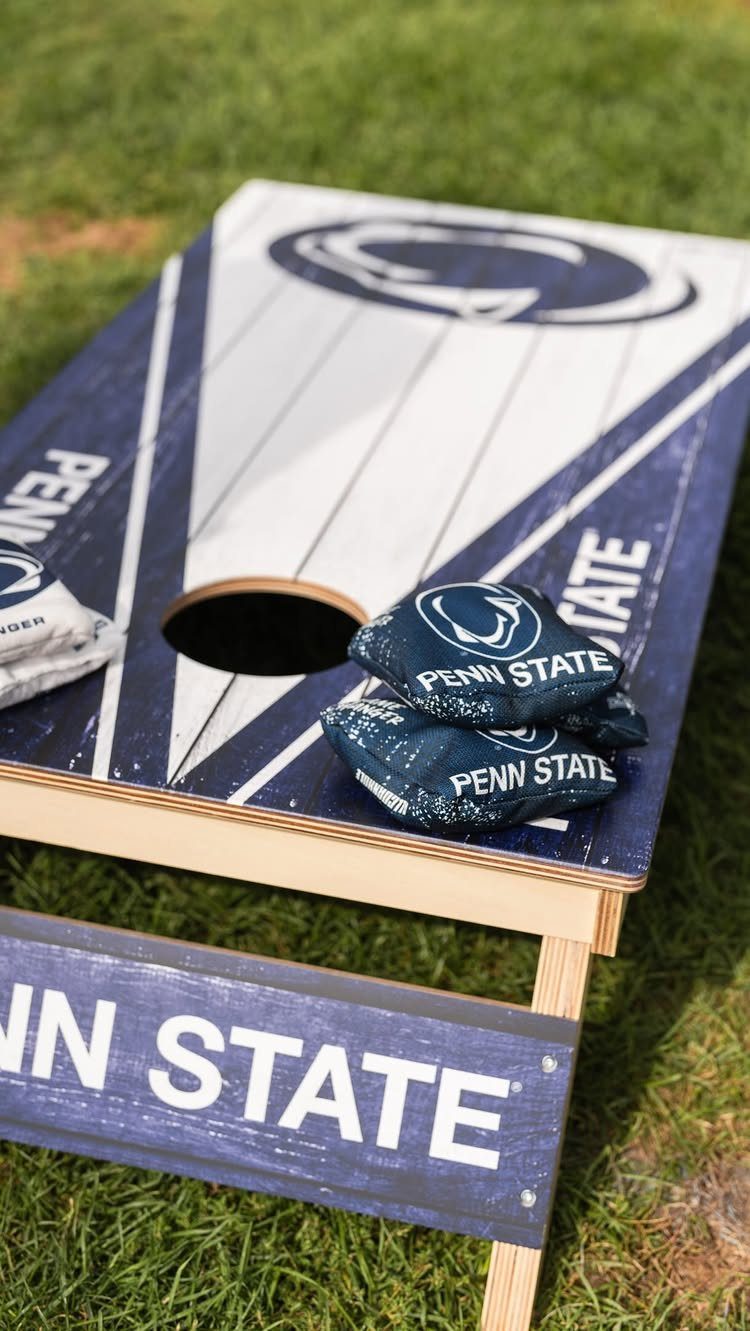 Penn State themed cornhole board with matching bean bags on green grass.