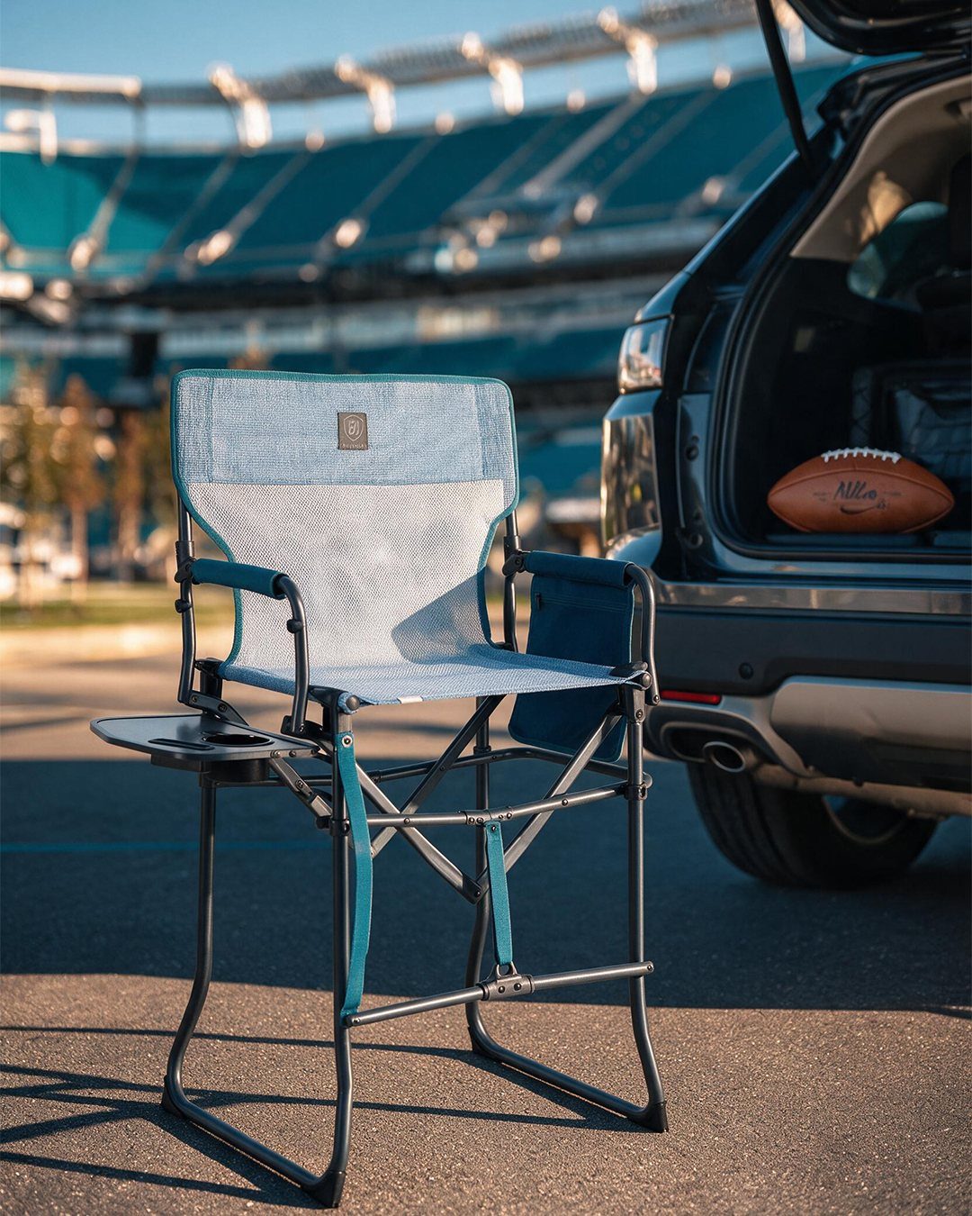 Blue and grey folding camp chair next to an SUV at a stadium