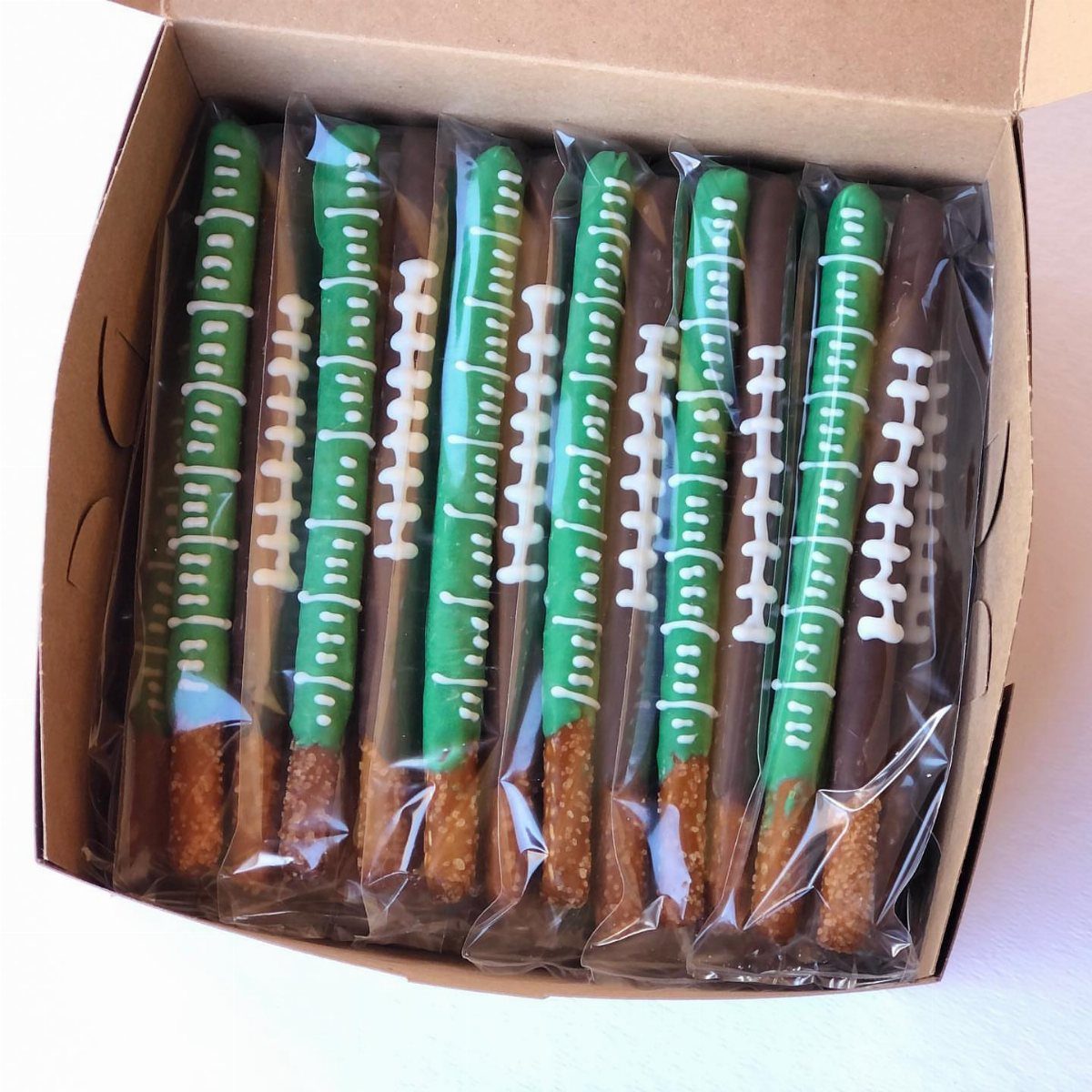 Chocolate covered pretzel rods decorated as football fields in a cardboard box