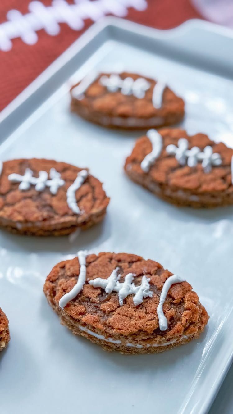 Football shaped cookies with white icing on a white platter and red background