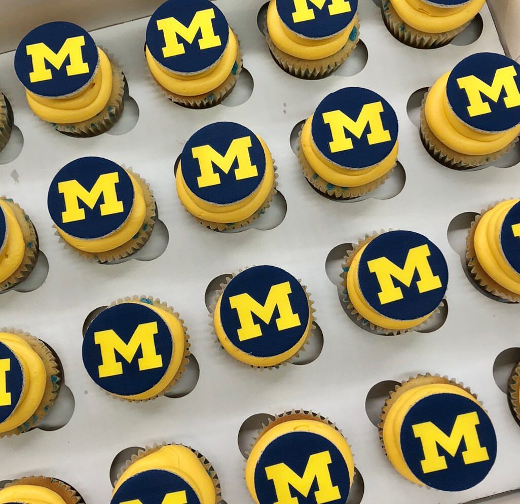 Cupcakes with yellow frosting and blue discs featuring a yellow letter M.