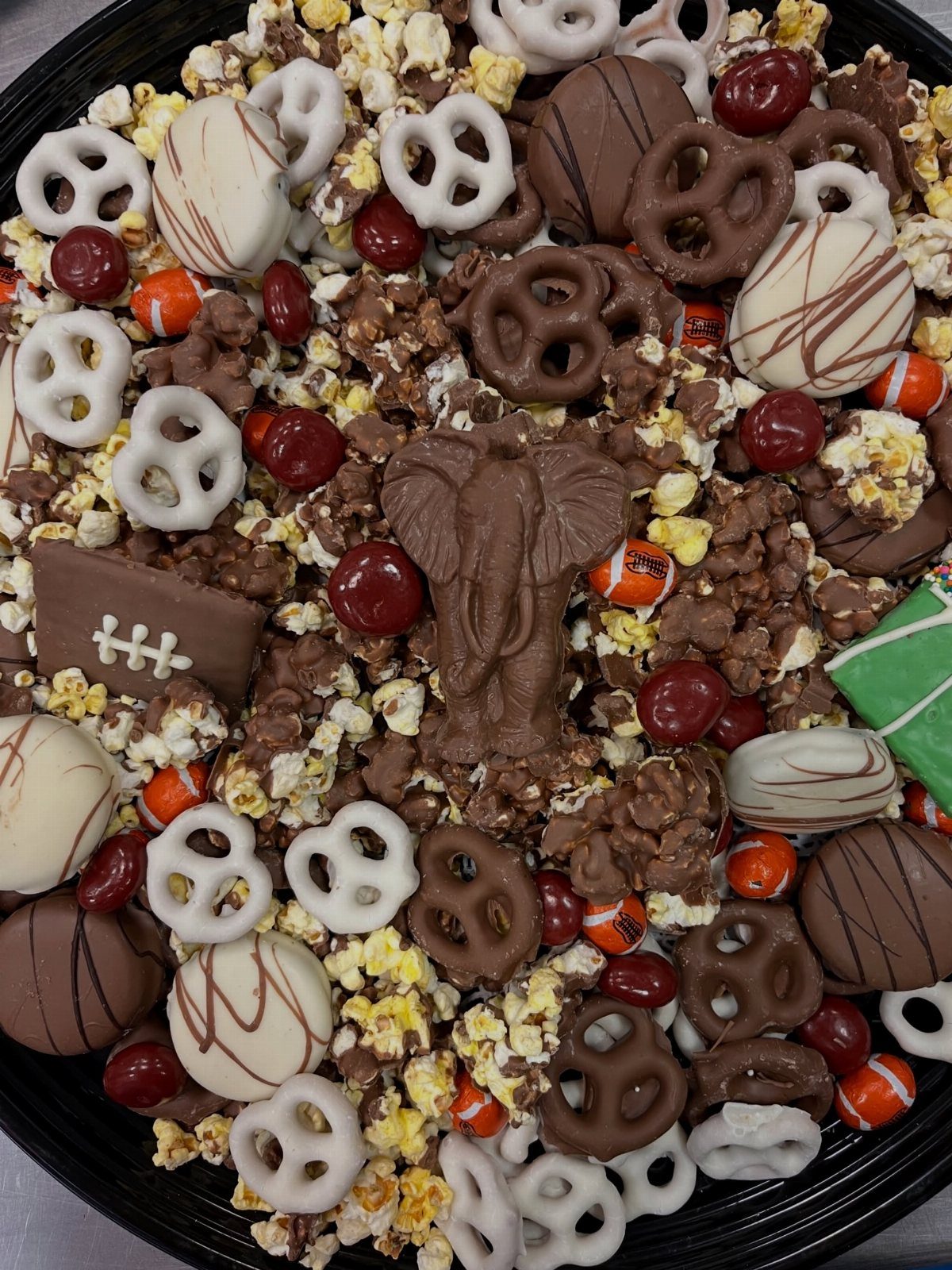 Assorted chocolate treats, pretzels, and popcorn on a platter with a chocolate football.