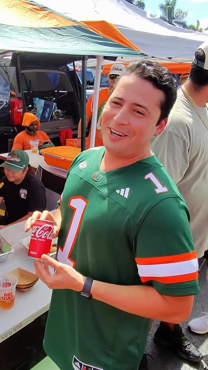 Man in green football jersey holding a red soda can at a tailgate party
